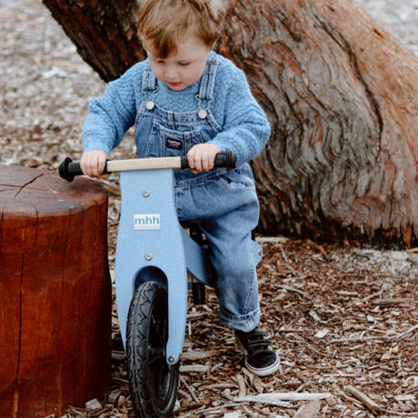 young child engaged in play with balance bikes at home