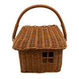 A brown woven wicker basket with a house-shaped design, featuring a small window cutout on the front and a curved top handle, isolated on a white background.