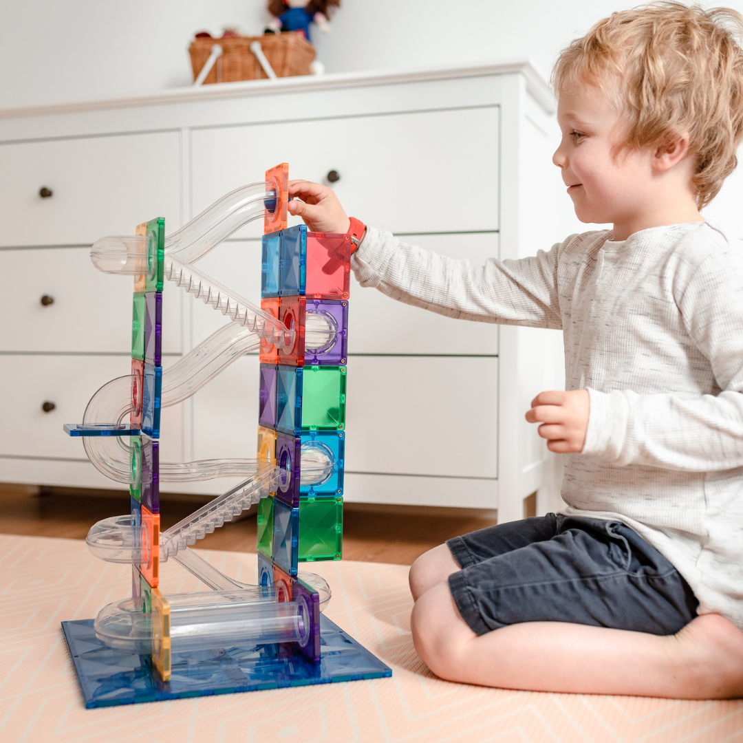 Three year old building creatively with magnetic tiles
