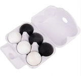 A white styrofoam egg carton holding six eggs, four black and two white, photographed on a plain white background.
